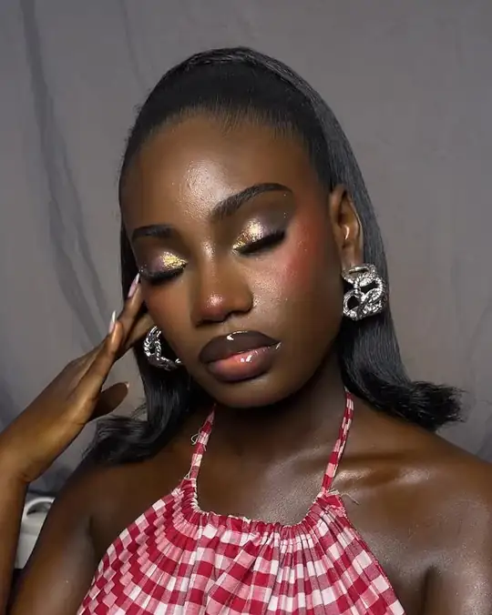 Gold lids and glossy lips on a woman in red gingham